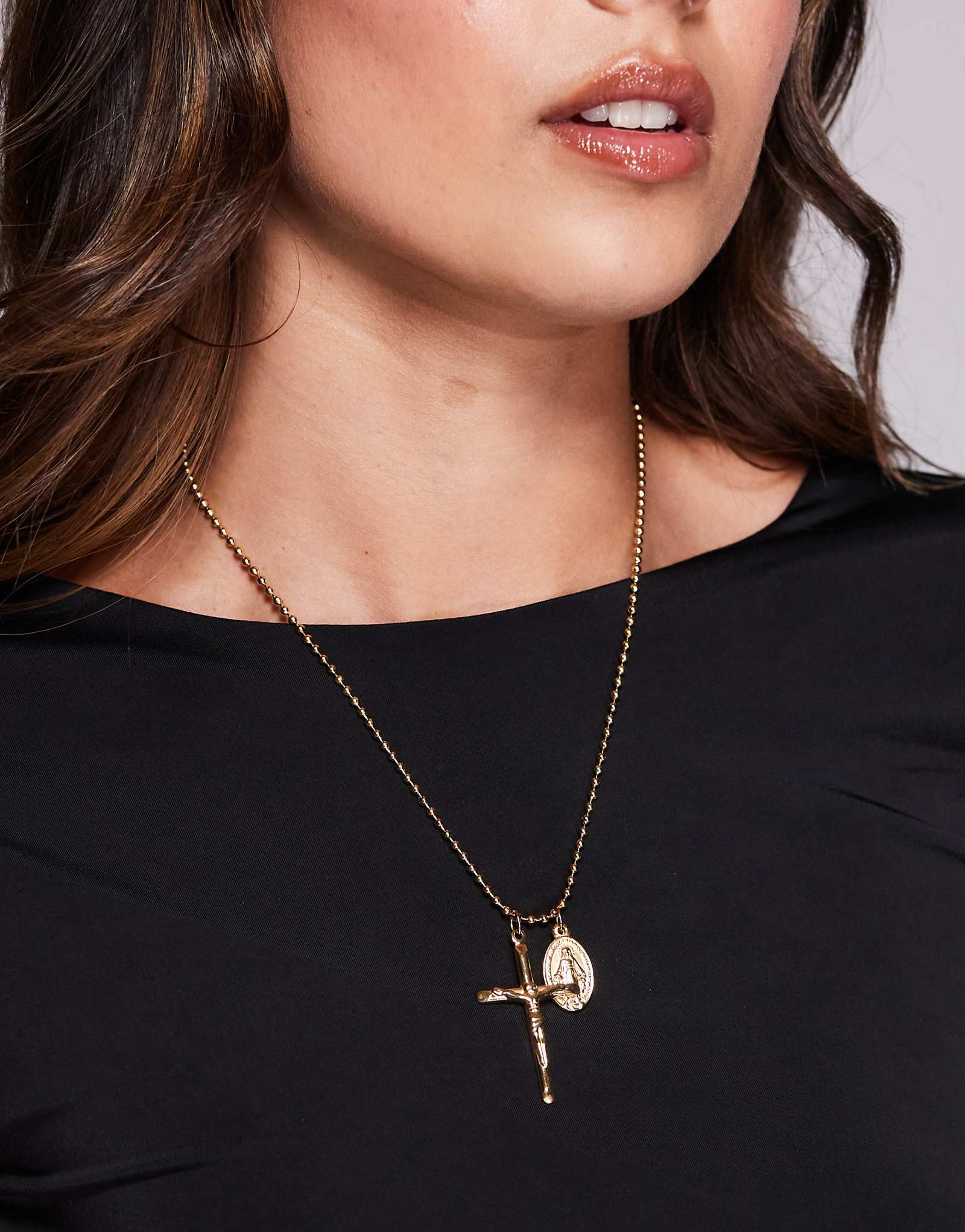 На шее - позолоченный крестик из нержавеющей стали и ожерелье с подвеской из золота