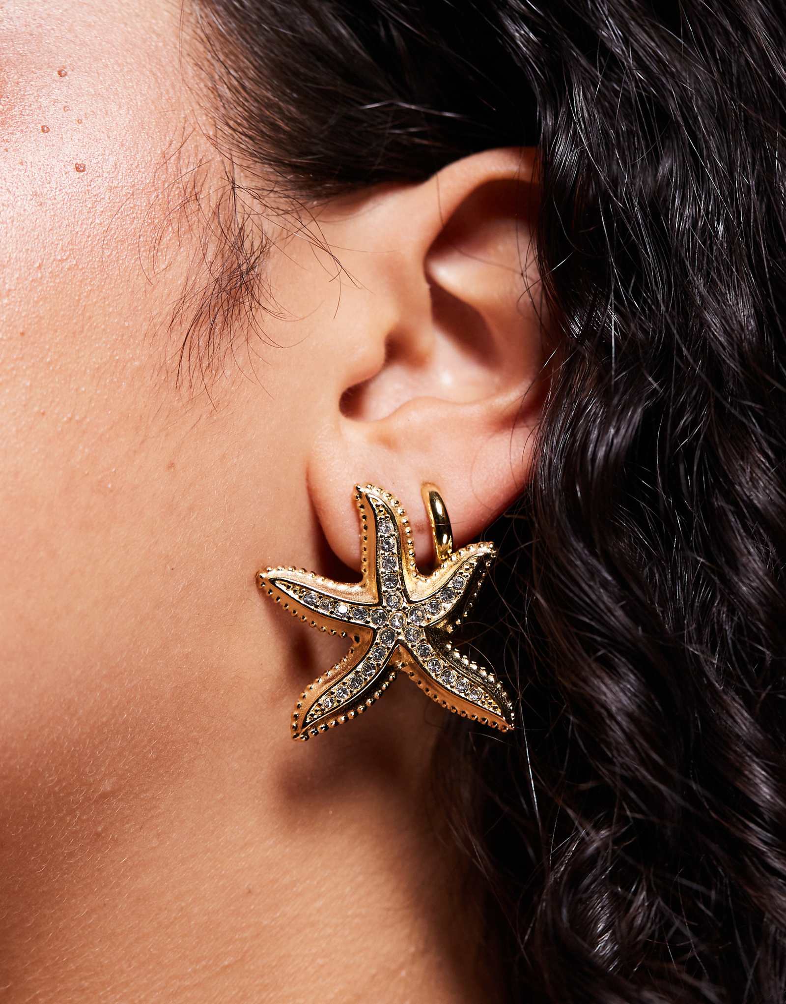 Линия шеи украшена эффектными серьгами в виде морских звезд в золотой оправе 9990₽