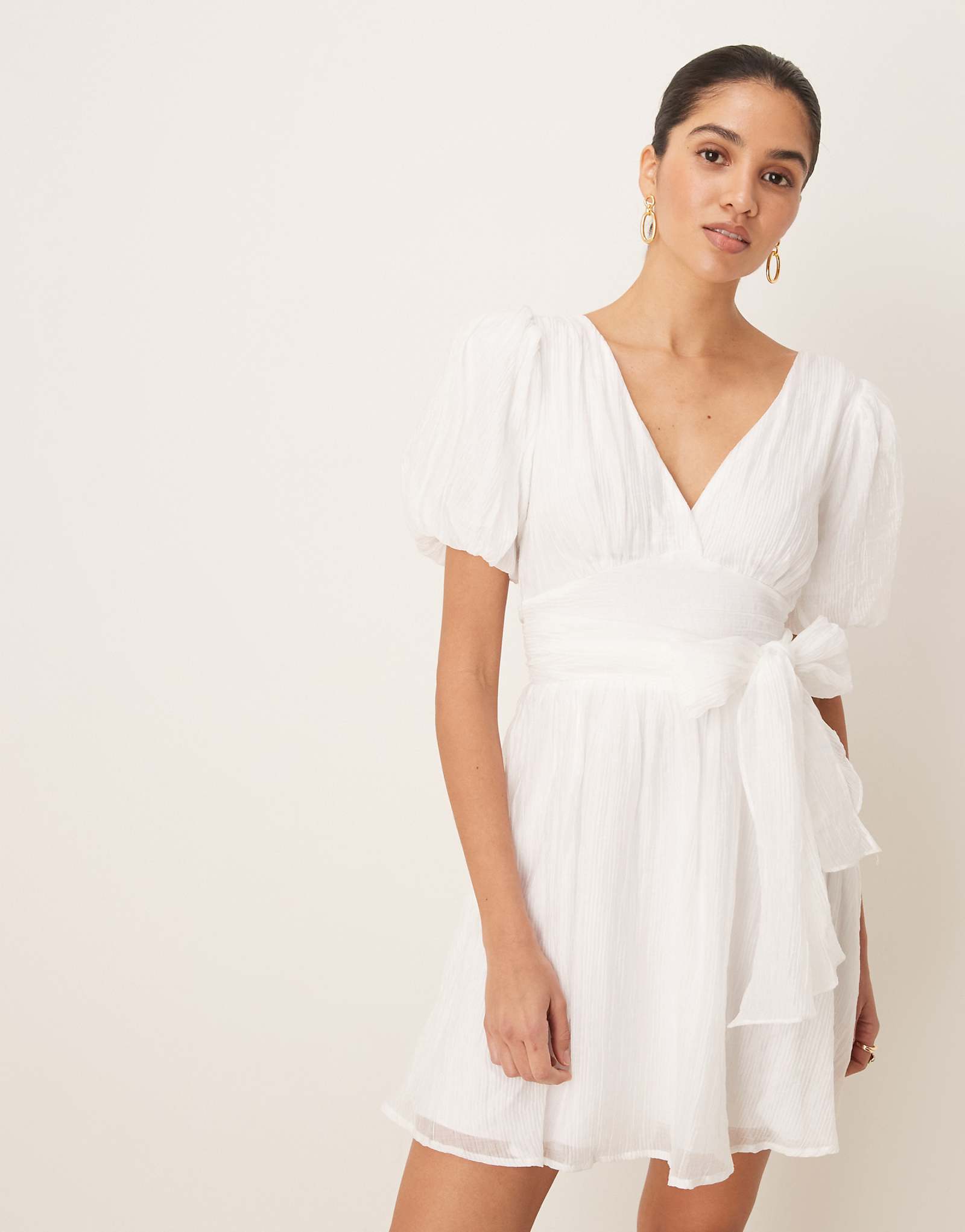 Выпускное мини-платье из трикотажа Gina с коротким рукавом и v-образным вырезом и открытой спиной и бантом белоснежного цвета 11190₽